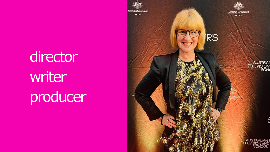 A blonde woman stands in front of the AFTRS media wall. She is wearing a black and gold sequin top with a black dinner jacket. Beside her in write writing with a hot pink background it says Director, Writer, Producer